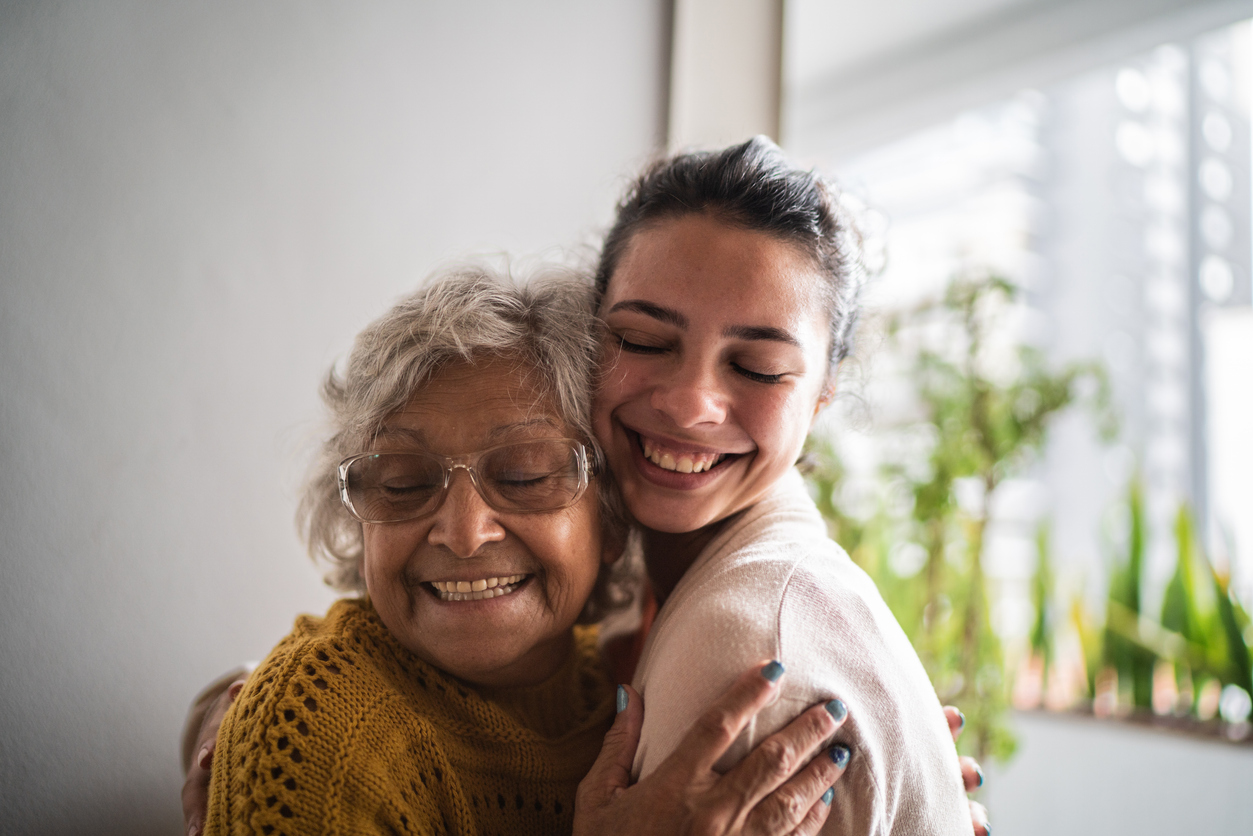 Grandmother hugging granddaughter at home