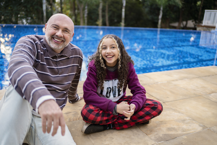 Portrait of father and teenage daughter near the swimming pool.